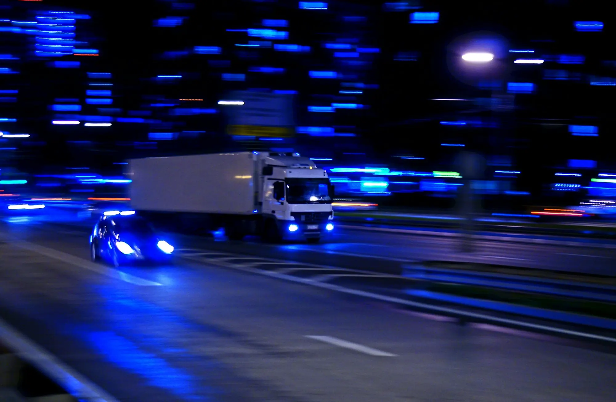 Caminhão trafegando à noite com luzes azuis em movimento